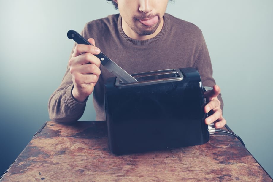 Person holding a knife inside a toaster