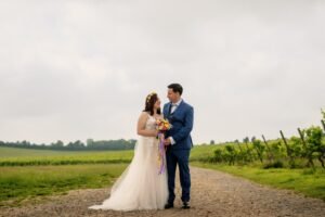 Couple in wedding clothes standing together on a vineyard path
