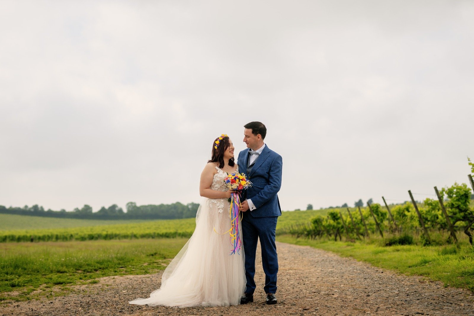 Couple in wedding clothes standing together on a vineyard path