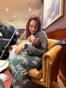 Parent bottle-feeding a baby while sitting in a café