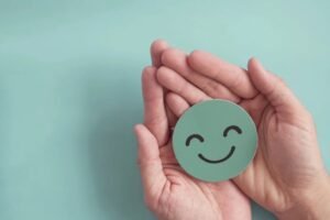 Hands holding a green smiling face symbol