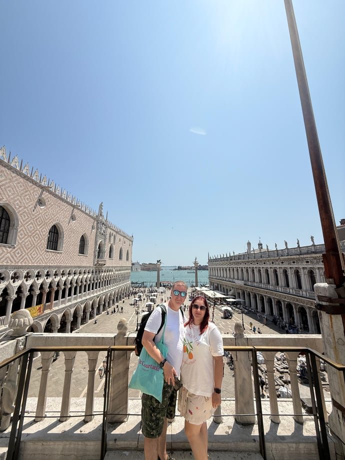 Couple standing on a balcony overlooking St Mark’s Square in Venice